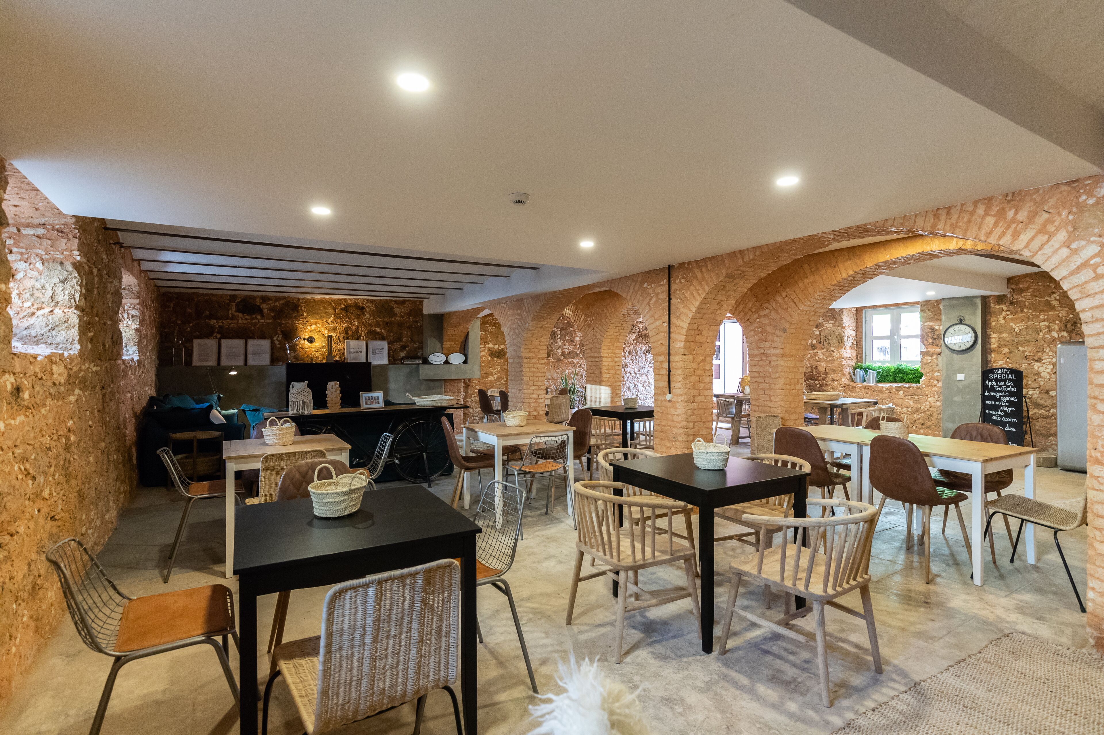A cozy restaurant with brick walls, wooden tables, and wicker chairs.