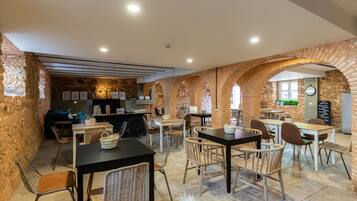A cozy restaurant with brick walls, wooden tables, and wicker chairs.