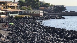 A rocky beach with a building in the background.