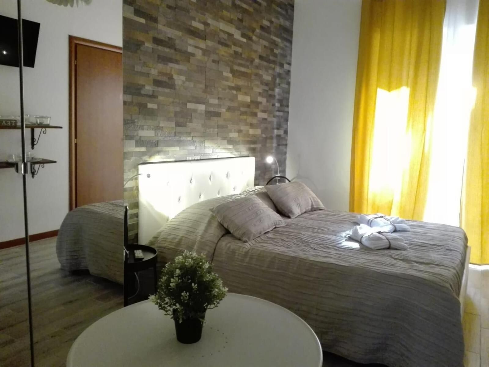 Un dormitorio moderno con un cabecero capitonado, una mesa redonda blanca y una planta en maceta.