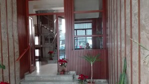A staircase leading to an upper floor, flanked by potted plants and a window with a view of the outside.