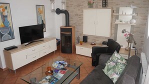 A modern living room with a flat-screen TV, a sofa, a coffee table, and a cabinet.
