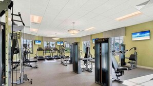 Ein Fitnessstudio mit Laufbändern, Kraftgeräten und einem großen Spiegel.