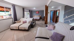A modern hotel room with a large bed, a sofa, and a separate bedroom area. - Family house, with pool views of the mountains 7 minut from the center Penedo RJ (Itatiaia)