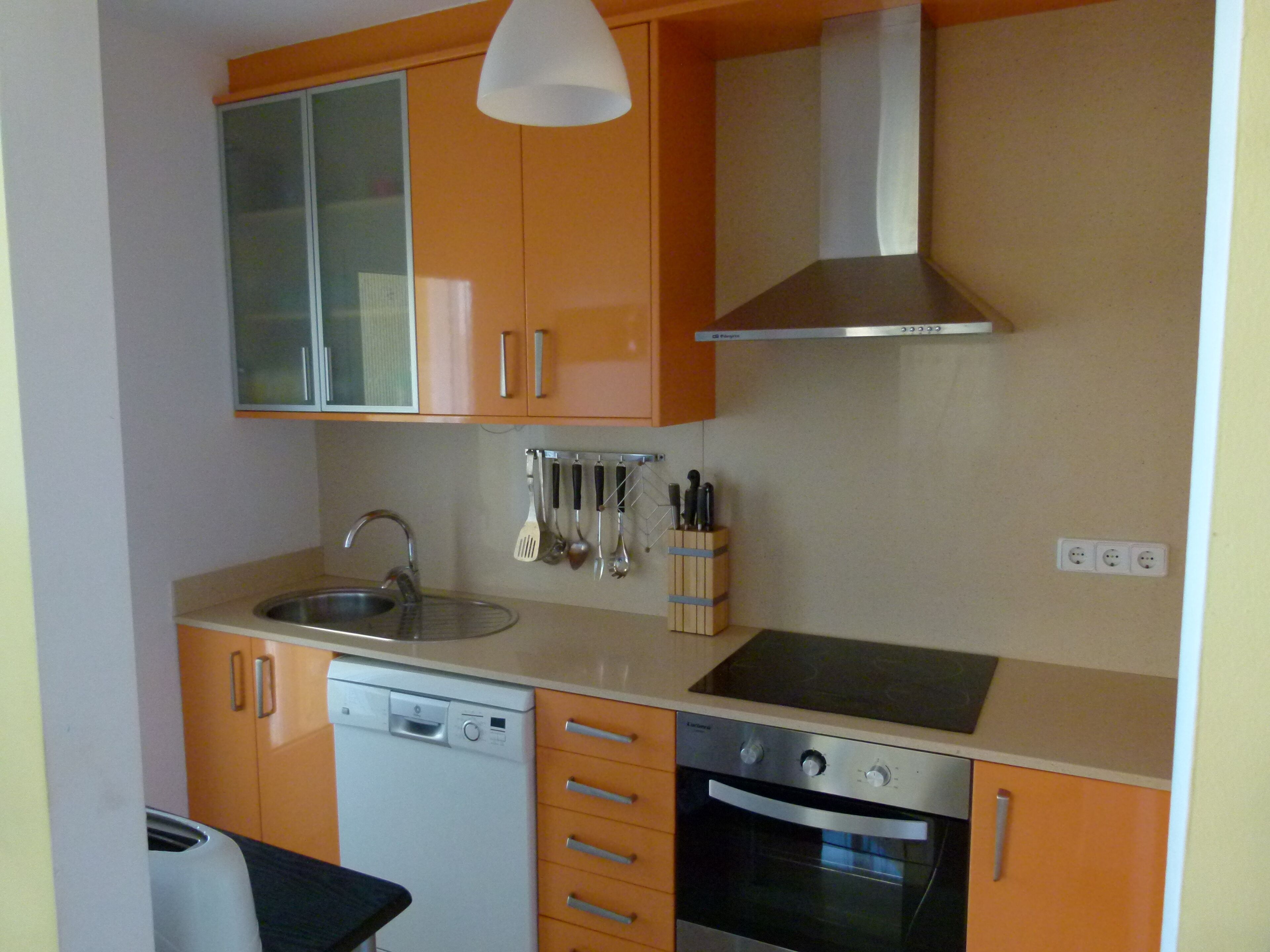 Una cocina compacta equipada con lavavajillas, horno y un colgador para utensilios.
