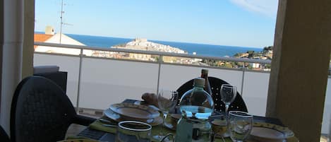Mesa para dos con vista al mar y un horizonte urbano distante.