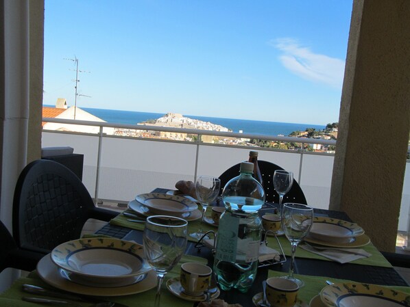 Mesa para dos con vista al mar y un horizonte urbano distante.