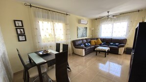 A living room with a sofa, a dining table with chairs, and a ceiling fan. - Family friendly, parking, beach, high-speed wifi, excursions, sea view ... (Peñíscola)