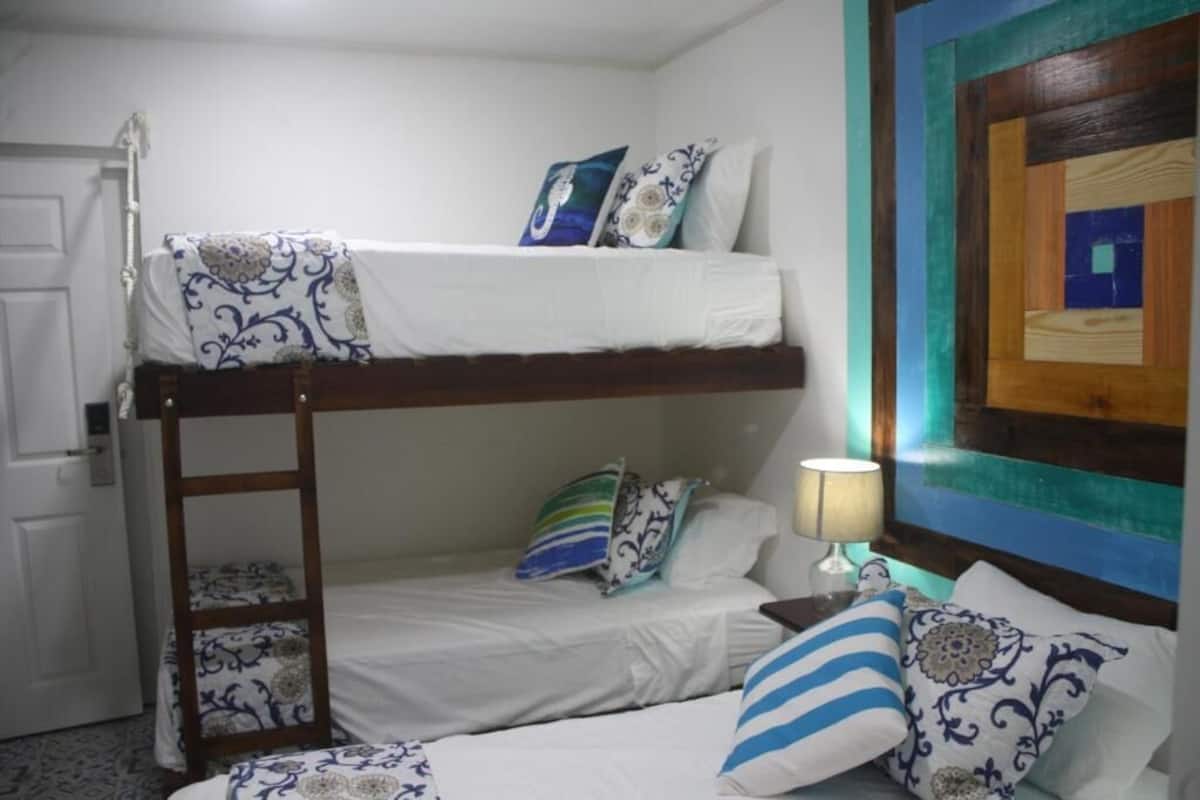 Quarto com beliche, escrivaninha com luminária e almofadas estampadas.
