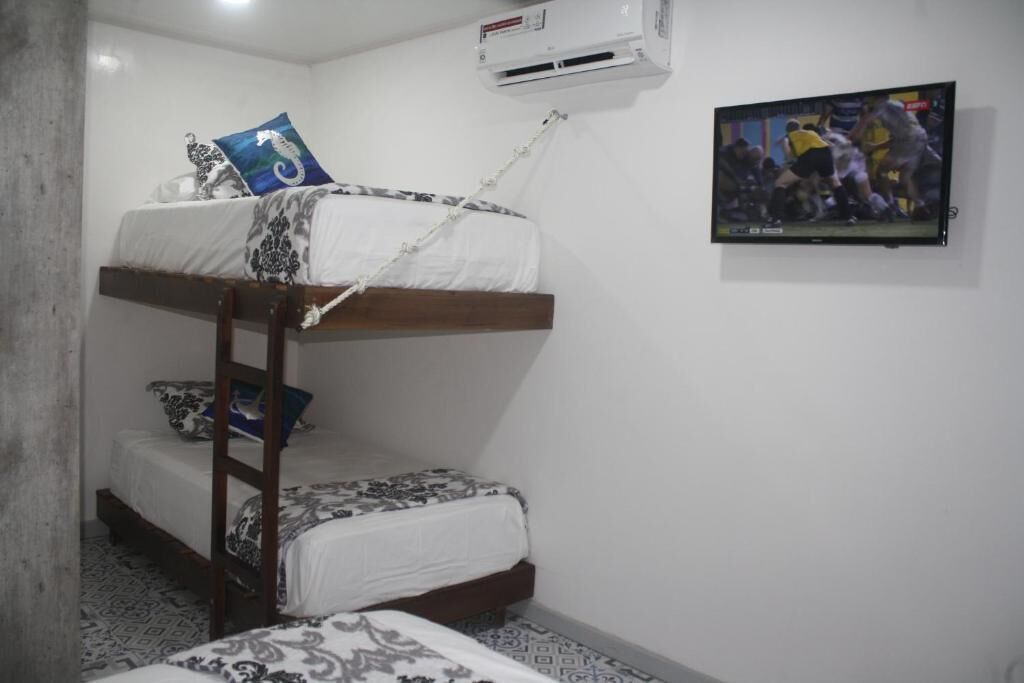 A room with bunk beds, a television, and an air conditioning unit.