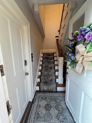 Stairs lead to an upper floor, flanked by white walls and a handrail.