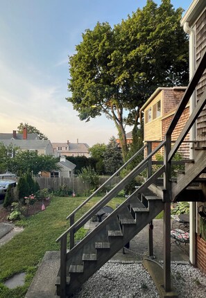 Staircase leads to an upper level, surrounded by a well-manicured lawn and lush greenery.