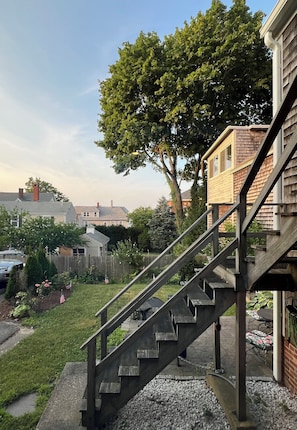 Staircase leads to an upper level, surrounded by a well-manicured lawn and lush greenery.
