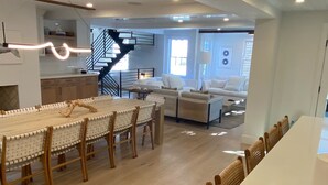 A spacious living area with a large dining table, a staircase, and a cozy seating area. - 100 Steps to Main Street. 5 bedrooms and 6.5 baths. New and Completely renovated (Nantucket)