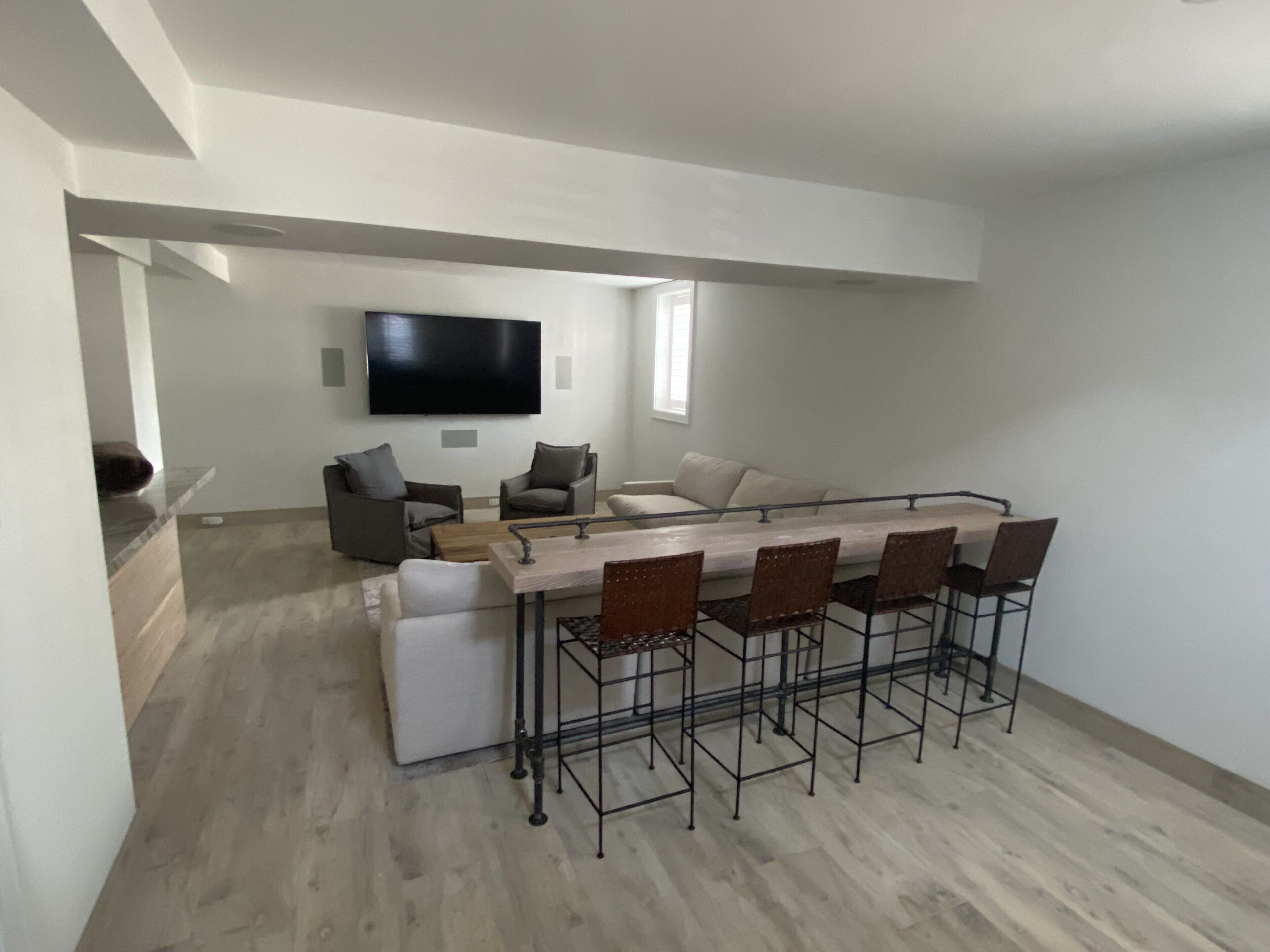 Una cocina moderna con una isla central, taburetes de bar y un televisor de pantalla plana montado en la pared.