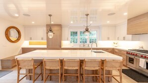 A spacious kitchen with a large island, wooden chairs, and modern appliances. - 100 Steps to Main Street. 5 bedrooms and 6.5 baths. New and Completely renovated (Nantucket)