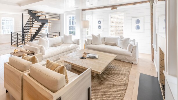 A spacious living room with a staircase, white sofas, a coffee table, and a large window. - 100 Steps to Main Street. 5 bedrooms and 6.5 baths. New and Completely renovated (Nantucket)