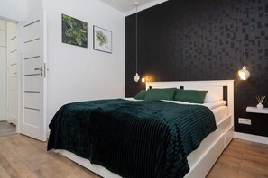 Un dormitorio con cama, armario blanco y dos lámparas fijadas a la pared.