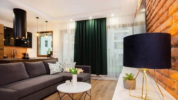 A modern living room with a sofa, a round coffee table, a black floor lamp, and a brick wall.