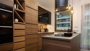 A modern kitchen with wooden cabinetry, a built-in oven, and a large island with a sink.