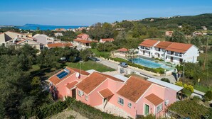 A coastal residential area with houses, a swimming pool, and a clear view of the sea.