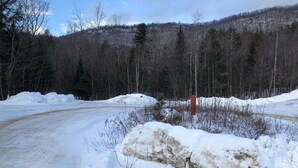 A snowy landscape with a road curving through a forested area. - Cycladic Sunday Chalet (Bethel)