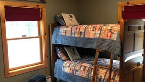 A bunk bed room with a ladder, a window with red curtains, and a ceiling light. - Cycladic Sunday Chalet (Bethel)