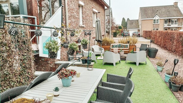 Eine Terrasse mit Gartenmöbeln, Topfpflanzen und einer Backsteinmauer.