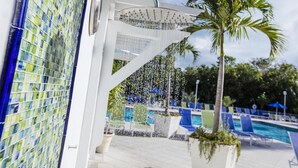 A pool area with a water feature, palm trees, and lounge chairs.