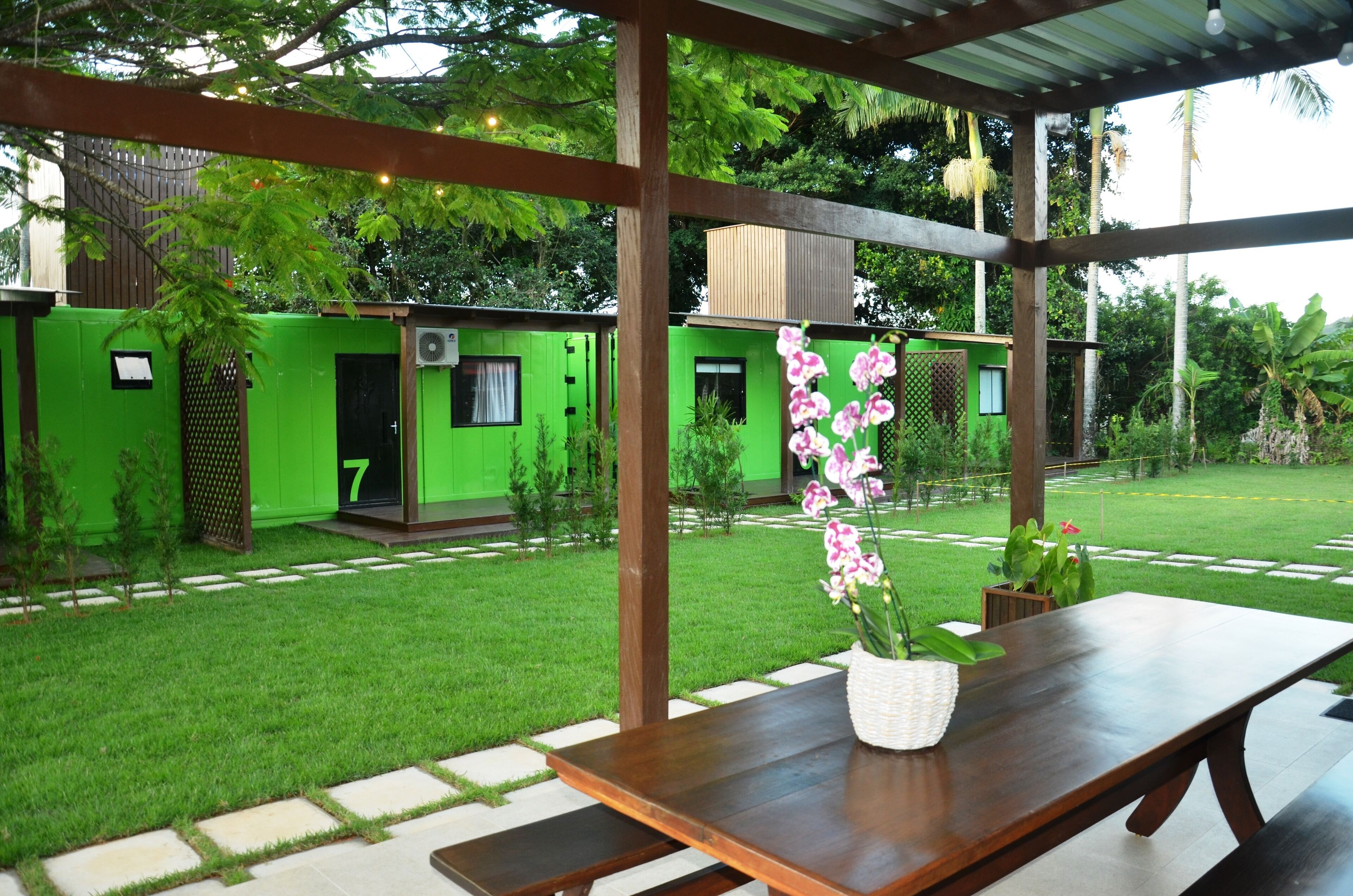 Un patio techado con una mesa de madera y una orquídea en maceta.