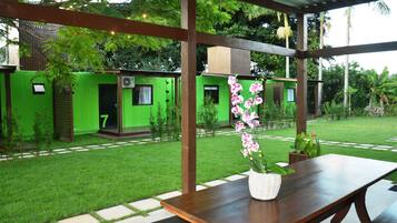 Un patio techado con una mesa de madera y una orquídea en maceta.