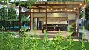 Een moderne buitenkeuken met een pergola, zitplaatsen en potplanten.