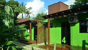 Een groen gebouw met een bord waarop het cijfer '4' staat, omringd door weelderige begroeiing en palmbomen.