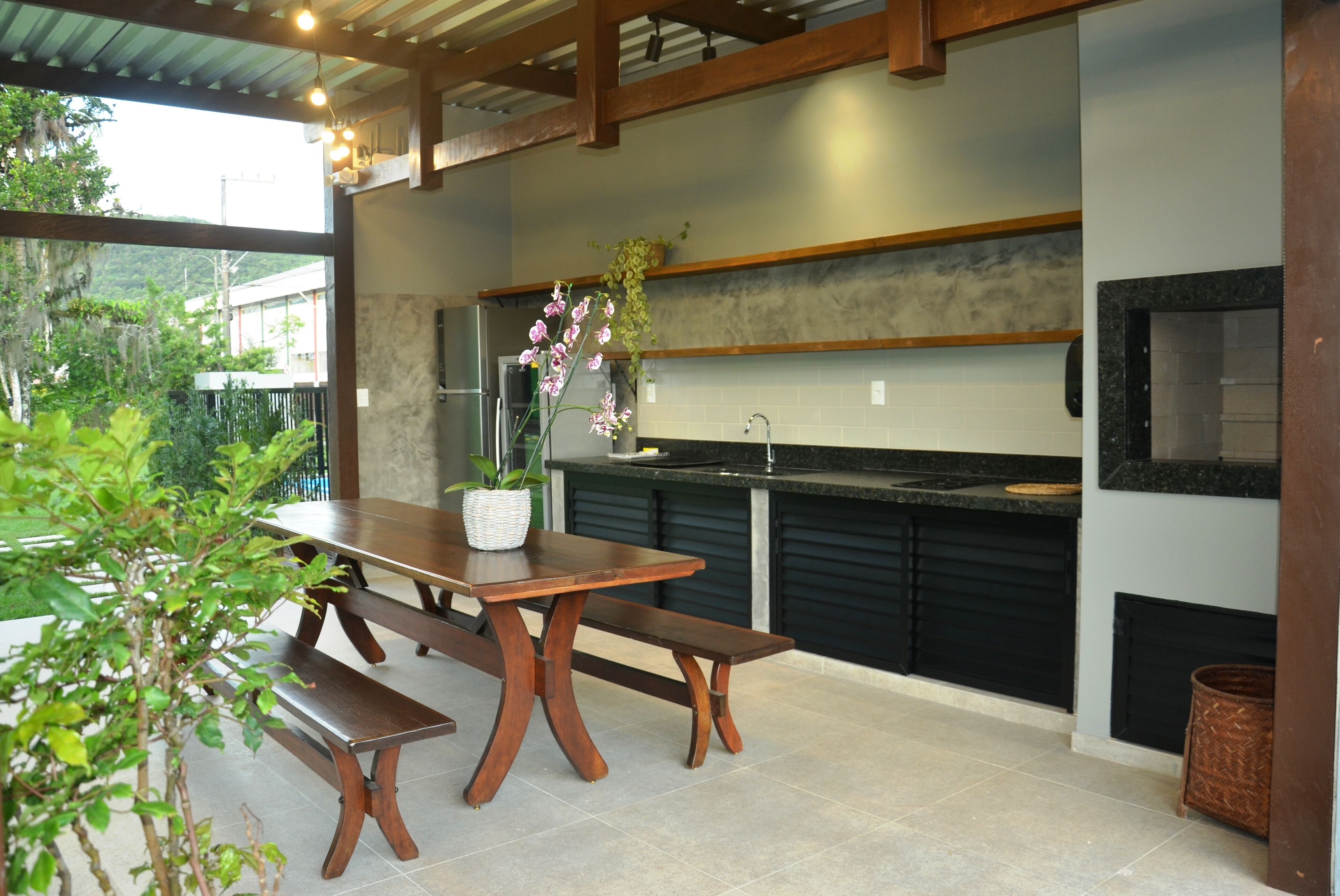 A modern kitchen with a wooden table and bench, a sink, and a potted orchid.