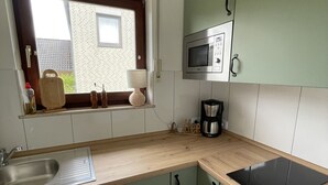Una cocina con ventana, microondas, cafetera y fregadero.