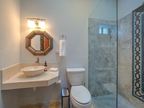 A bathroom with a marble sink, a toilet, and a glass shower enclosure.