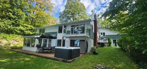 A two-story house with a deck, outdoor seating, and a hot tub.