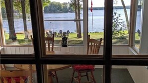 Une pièce dotée d’une grande fenêtre donnant sur un lac, d’une table en bois et de deux chaises.
