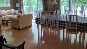 Un salon avec un canapé, une table à manger et des chaises, ainsi que de grandes fenêtres.