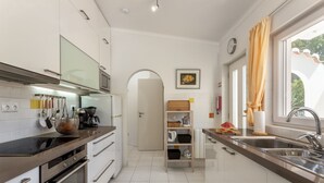 Eine moderne Küche mit Edelstahlgeräten, weißen Schränken und einem großen Fenster mit Vorhängen.