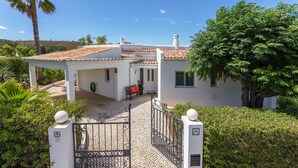Eine weiße Villa mit einem Ziegeldach, einer überdachten Terrasse und einem verschlossenen Eingang.