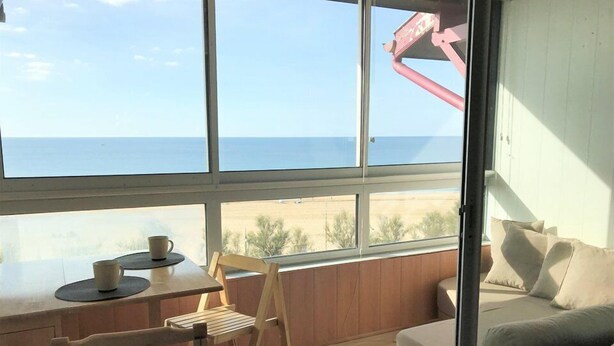 Quarto com vista para o oceano, uma escrivaninha de madeira com duas cadeiras e um sofá.