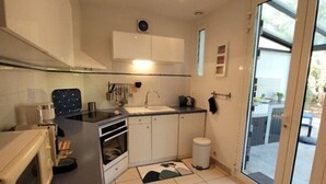 Una cucina compatta con mobili bianchi, un forno a microonde e un lavello.