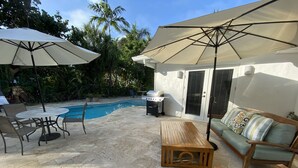 Ein Garten mit Pool, Gartenmöbeln und Sonnenschirmen.