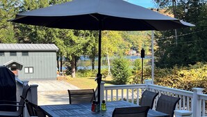 Un terrazzo con tavolo e sedie, un ombrellone e un barbecue.
