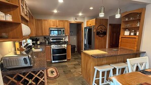 Una cucina moderna con mobili in legno, elettrodomestici in acciaio inossidabile e un'isola centrale con sgabelli da bar.