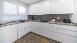 A modern kitchen with white cabinets, a grey countertop, a sink, and a window providing natural light. - Elvira: Pleasant house with communal pool located in a quiet area (L'Escala)