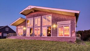 Une maison moderne à deux étages, dotée de grandes fenêtres, d’un porche abrité et d’un intérieur bien éclairé.