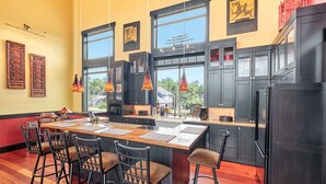 Une cuisine moderne dotée d’un îlot central, de meubles de couleur noire et de luminaires suspendus.
