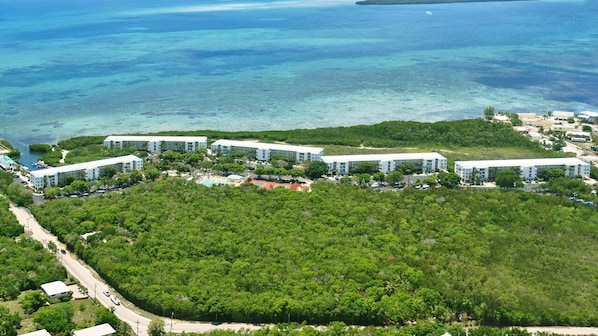 An aerial view of a resort with multiple buildings, a swimming pool, and lush greenery surrounding the property.